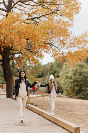 stylish mom and daughter walk together in the autumn park by the handの写真素材