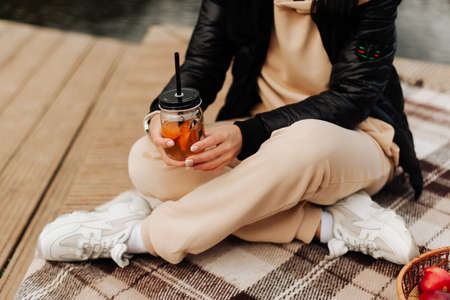 mug with a straw in the hands of a girl autumn picnic close-upの写真素材
