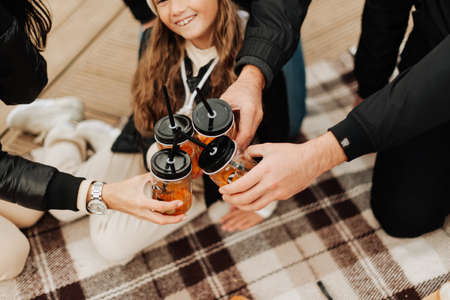 happy family having picnic hands holding glasses with straws autumn picnicの写真素材