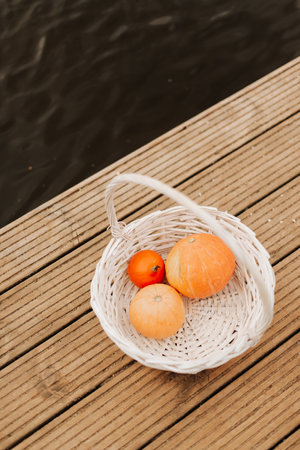 three pumpkins of different sizes in a white wicker basket autumnの写真素材