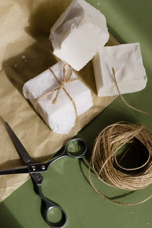 handmade soap of white color beautifully packaged and scissors on a green background