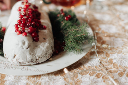 beautiful festive table close-up christmas stollen with red berriesの写真素材