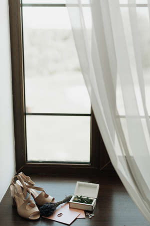 wedding shoes and rings lie on the windowsill near the window close-upの写真素材