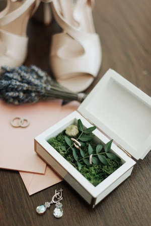 wedding rings and earrings of the bride lie on the table close-upの写真素材