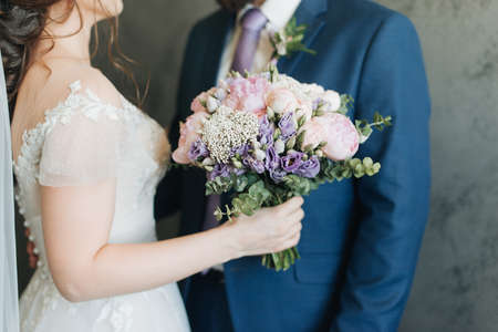 stylish groom in a blue jacket and the bride with a bouquet in their hands wedding dayの写真素材