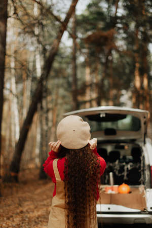 stylish girl with long hair and in a white beret stands in the autumn forestの写真素材