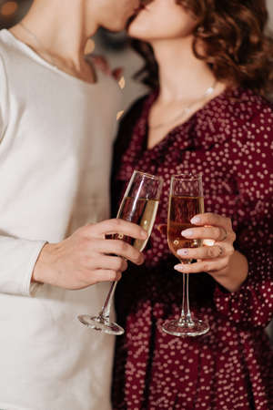 stylish man and woman holding glasses of champagne and kissingの写真素材
