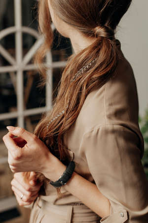 stylish thin girl in a dress and watches with long hair stands sidewaysの写真素材