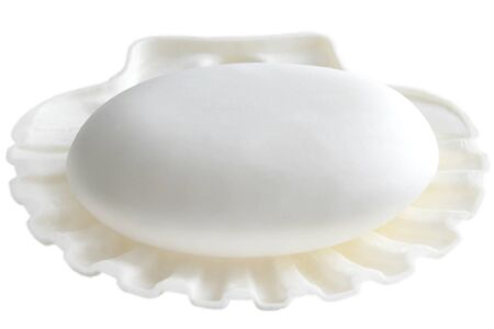 The white soap lays in a soap tray on a white background