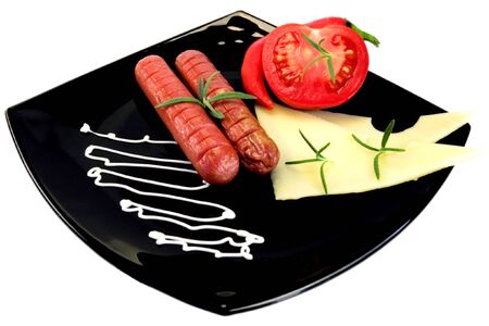two sausage with tomato and cheese on black plateの写真素材