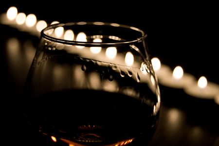 one glass of cognac in the candle burnの写真素材