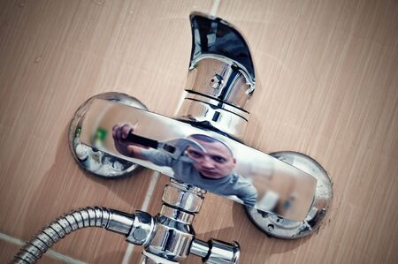 reflection of men with wrench in faucetの写真素材