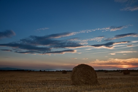 straw bale on field on sunset timeの写真素材