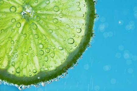 lime with bubbles on blue backgroundの写真素材