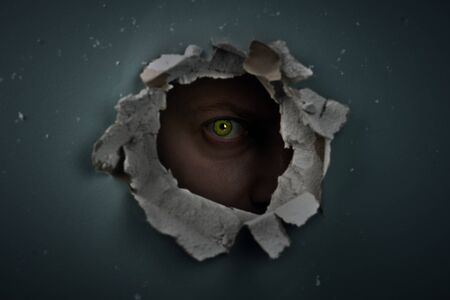 eye behind hole in the wallの写真素材