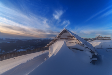 Fantastic pink evening landscape glowing by sunlight. Dramatic wintry scene with snowy house. Carpathians, Ukraine, Europe.の写真素材