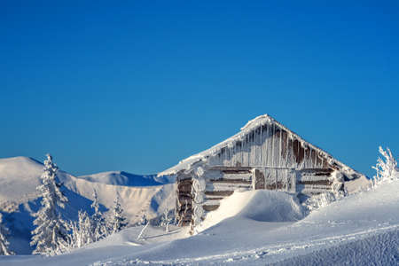 Fantastic pink evening landscape glowing by sunlight. Dramatic wintry scene with snowy house. Carpathians, Ukraine, Europe.の写真素材