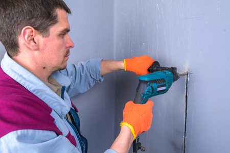 worker drills a wall in houseの写真素材