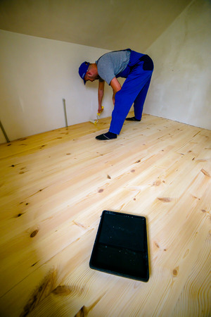 Wooden floor varnished. Worker with paint roller.の写真素材