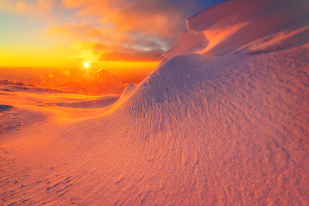 Fantastic orange evening landscape glowing by sunlight. Dramatic wintry scene with snowy trees. Carpathians, Ukraineの写真素材
