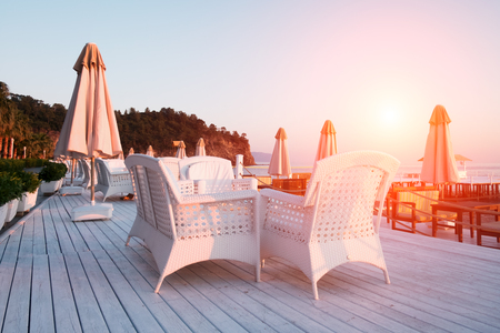 Summer restaurant on beach. Breathtaking view on mediterranean sea. White wooden terrace and braided furnitureの写真素材