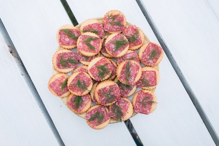 Heap of snack with salami and dill on white wood tableの写真素材