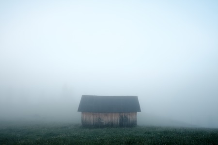 Alone house on foggy meadowの写真素材