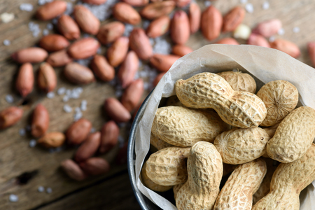 Salted peanuts are peeled and inshelled on a paper bag. Studio macro shoot. Food photography