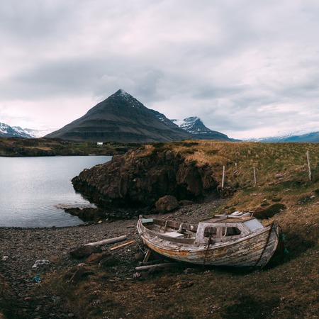 Typical Iceland landscape with fjord, mountains and old ship