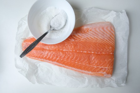 Fillet of salmon fish on white table with knife and saltの写真素材