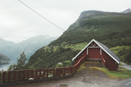Red garage in norwegian Geiranger village in western Norway. Sunnylvsfjorden fjord from high...