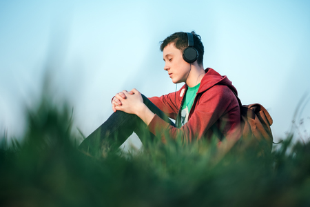 Teenager on green lawn listening music in headphones. Happy dreamerの写真素材