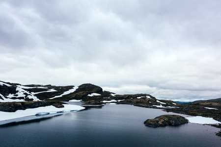 Typical norwegian landscape with snowy mountains and clear lake near the famous Aurlandsvegen (Bjorgavegen), mountain road, Aurland, Norway.の写真素材