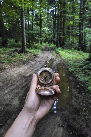 Man with compass in hand in lush summer forest. Travel conceptの写真素材