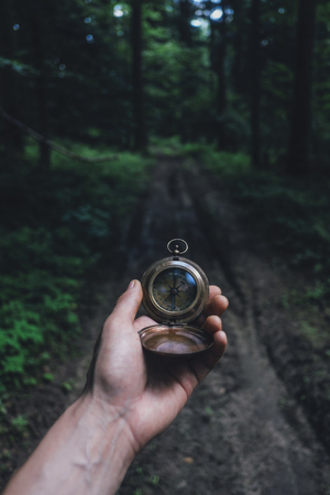 Man with compass in hand in lush summer forest. Travel conceptの写真素材