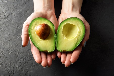 Fresh avocado fruit in girl hands. The concept of healthy eating. Food photographyの写真素材
