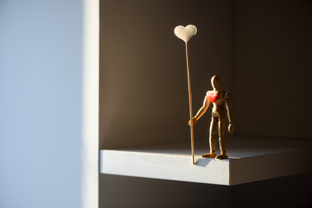 Wooden man figure with red heart on his breast. Valentines day background, creative texture and love conceptの写真素材