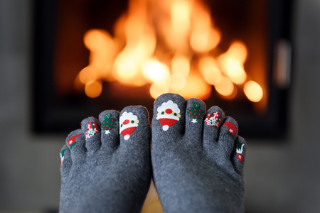 Burning fireplace and girl feet in funny wool socks on foreground. Hygge conceptの写真素材
