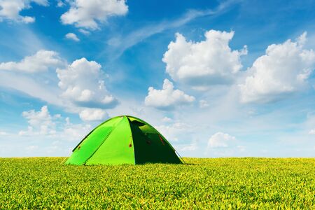 Green tent on summer meadow on blue cloudy sky background. Amazing green highland. Landscape photographyの写真素材