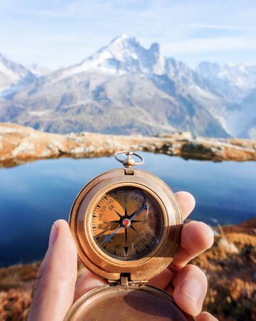 Man with compass in hand in high mountains near clear lake. Travel concept. Landscape photographyの写真素材