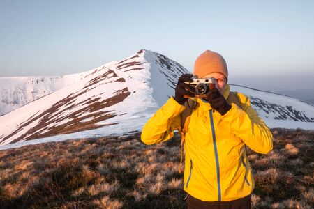 Photographer in yellow jacket taking photo on snowy winter field