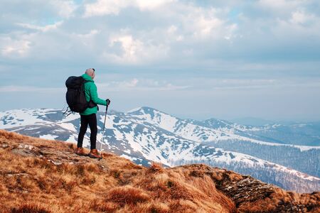 Amazing landscape with snowy mountains range and traveler with backpack on a foreground