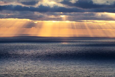 Sunset in the ocean with glowing sun rays and cloudy sky. Sea sunrise background. Landscape...