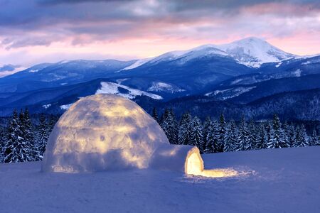 Real snow igloo house in the winter mountains. Snow-covered firs and mountain peaks on the...
