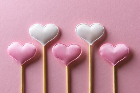 Pink textile hearts on wooden sticks closeup. Valentines day background, creative texture and love...