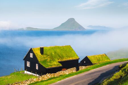 Foggy morning view of a house with typical turf-top grass roof in the Velbastadur village on Streymoy island, Faroe islands, Denmark. Landscape photographyの写真素材