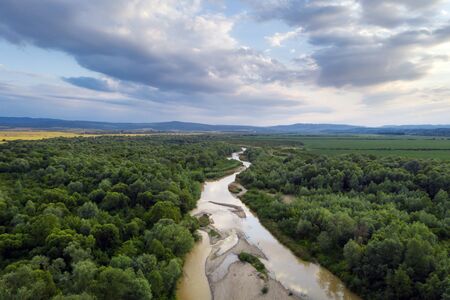Flight through majestic river Dnister and lush green forest at sunset time. Ukraine. Landscape...