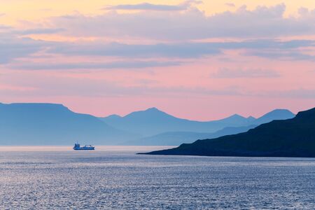 Beautiful summer sunset on Faroe Islands, Denmark. Lonely ship in the coastal waters. Landscape photographyの写真素材