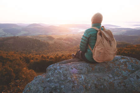 Alone tourist on the edge of the cliff against the backdrop of an incredible sunrise mountains...