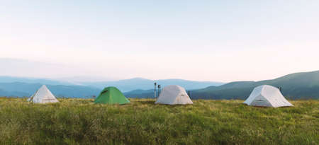 Four tents on amazing meadow in summer mountains. Tourists camp. Landscape photography, travel...